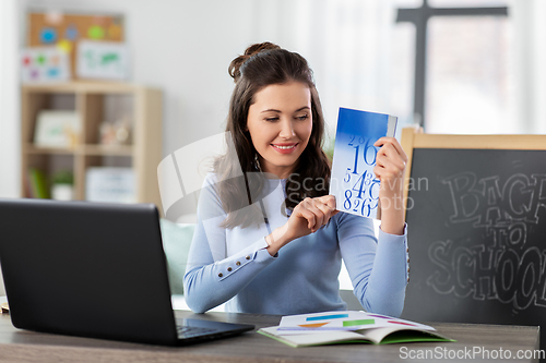 Image of math teacher with book having online class at home