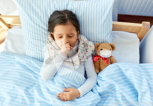 Image of sick coughing girl with teddy bear lying in bed