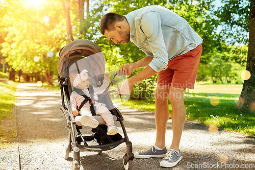 Image of father with child sitting in stroller at park