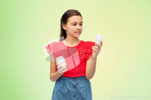 Image of smiling girl comparing different light bulbs