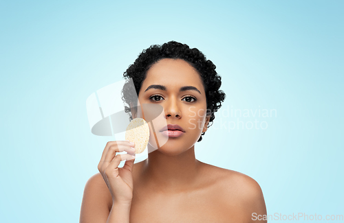 Image of young woman cleaning face with exfoliating sponge