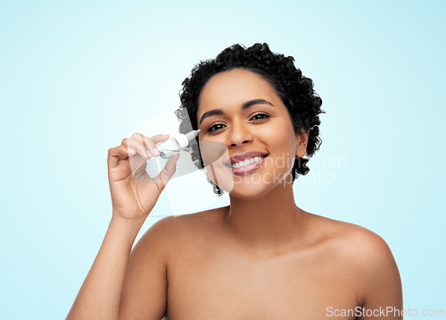 Image of happy young african american woman with eye drops