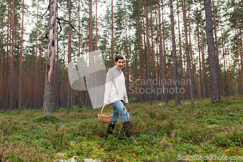 Image of woman with basket picking mushrooms in forest