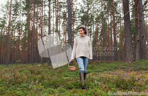 Image of woman with basket picking mushrooms in forest