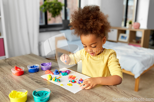 Image of little girl with modeling clay playing at home