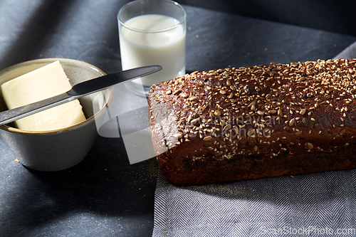 Image of close up of bread, butter, knife and glass of milk