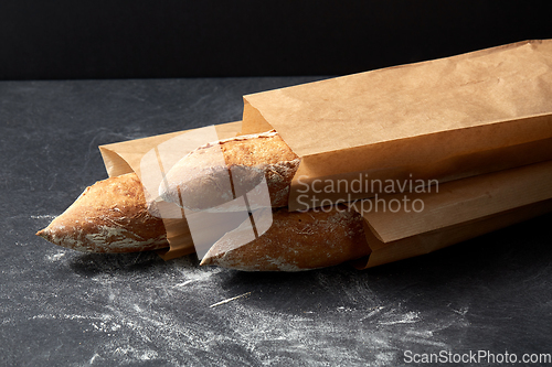 Image of close up of baguette bread in paper bags on table