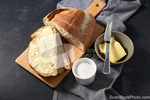 Image of close up of bread, butter, knife and salt on towel