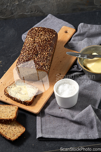 Image of close up of bread, butter, knife and salt on towel