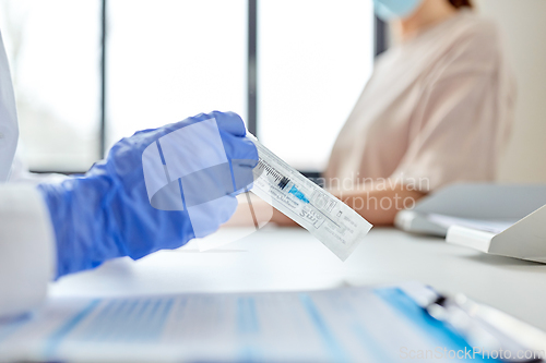 Image of female doctor with syringe and patient at hospital