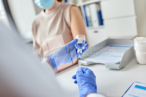 Image of female doctor with syringe vaccinating patient