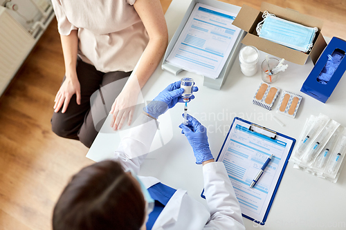 Image of female doctor with syringe vaccinating patient