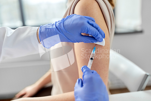 Image of female doctor with syringe vaccinating patient