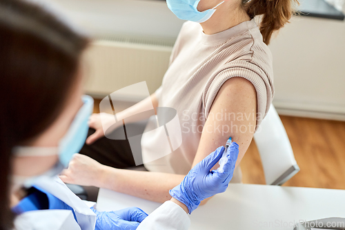 Image of female doctor with syringe vaccinating patient