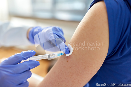 Image of doctor with syringe vaccinating medical worker