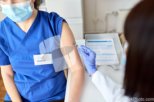 Image of doctor with syringe vaccinating medical worker