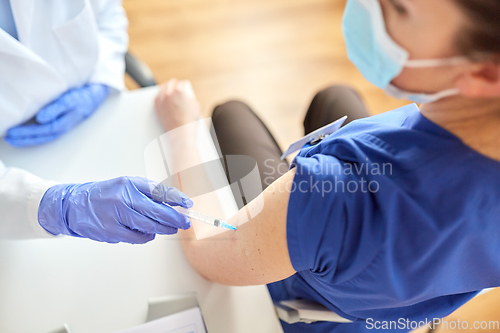 Image of doctor with syringe vaccinating medical worker