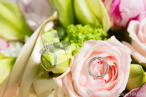 Image of wedding rings lie on a beautiful bouquet as bridal accessories