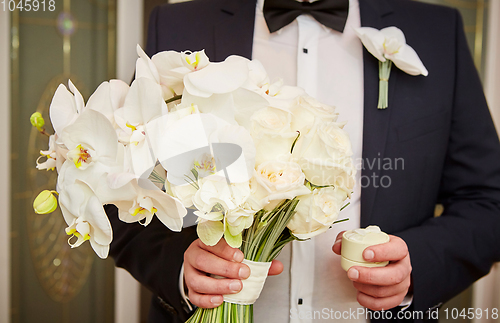 Image of groom with rings and bouquet