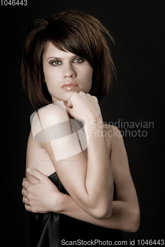 Image of the sexy strict woman with makeup and a fashionable hairstyle poses in studio on black background