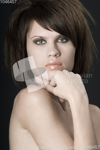 Image of the sexy strict woman with makeup and a fashionable hairstyle poses in studio on black background