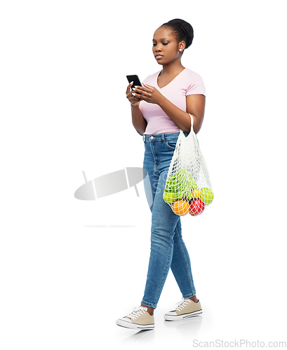 Image of woman with smartphone and food in string bag