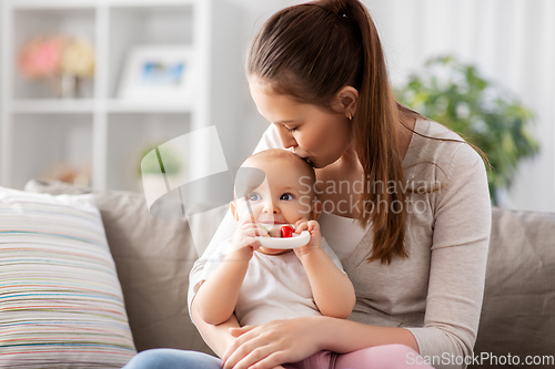 Image of mother kissing baby with teething toy at home