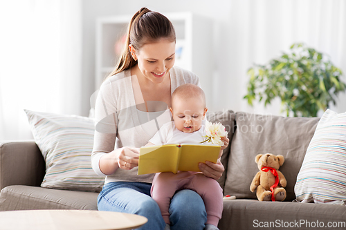 Image of happy mother reading book to little baby at home