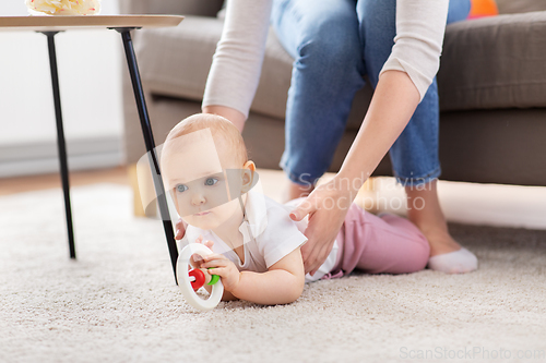 Image of mother and baby playing with rattle at home