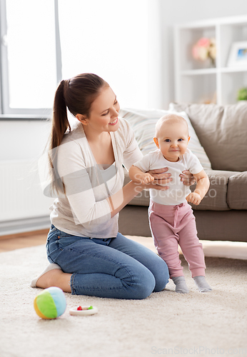 Image of happy mother playing with little baby at home