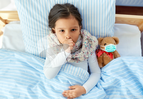 Image of sick coughing girl with teddy bear lying in bed