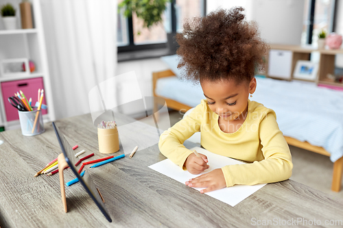 Image of little girl drawing with coloring pencils at home