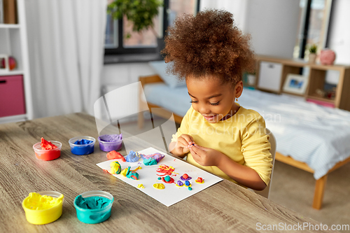 Image of little girl with modeling clay playing at home