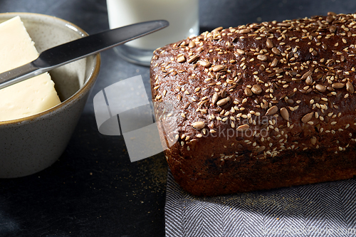 Image of close up of bread, butter, knife and glass of milk