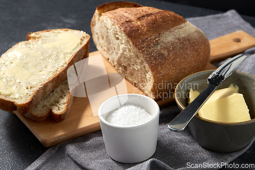 Image of close up of bread, butter, knife and salt on towel