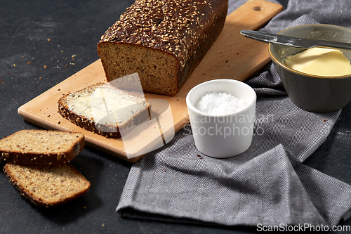 Image of close up of bread, butter, knife and salt on towel