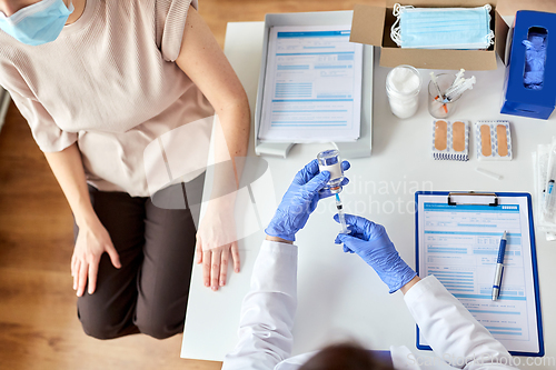 Image of female doctor with syringe vaccinating patient