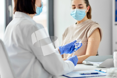 Image of female doctor with syringe vaccinating patient