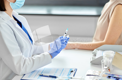 Image of female doctor with syringe vaccinating patient