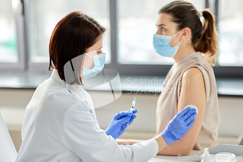 Image of female doctor with syringe vaccinating patient