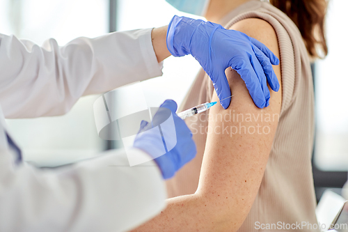 Image of female doctor with syringe vaccinating patient