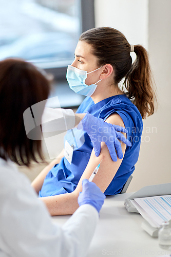 Image of doctor with syringe vaccinating medical worker