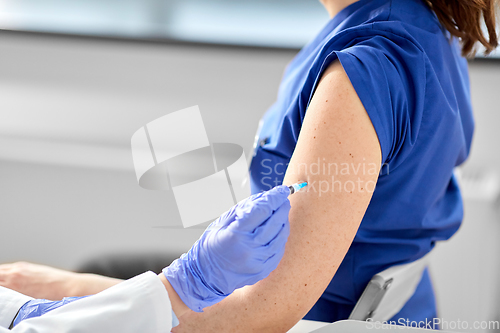 Image of doctor with syringe vaccinating medical worker