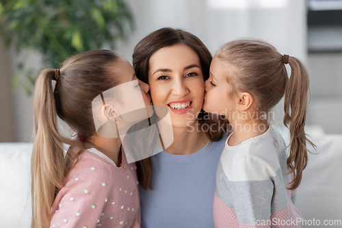 Image of happy mother and two daughters kissing her at home