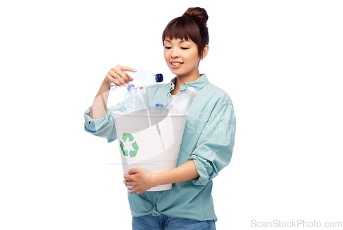 Image of smiling young asian woman sorting plastic waste