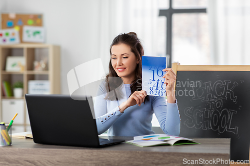 Image of math teacher with book having online class at home