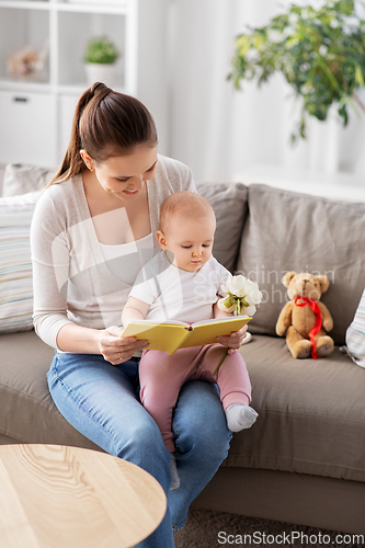 Image of happy mother reading book to little baby at home