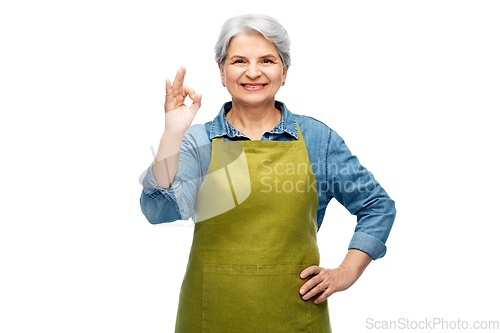 Image of senior woman in garden apron showing ok gesture