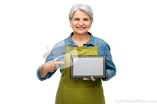 Image of happy senior woman in garden apron with tablet pc