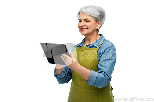 Image of happy senior woman in garden apron with tablet pc